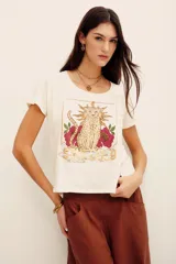 Remera blanca de algodón, de manga corta y corte recto, con estampa frontal que incluye un felino dorado rodeado de flores y la leyenda 'Stay Gold'.