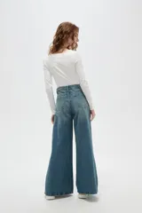 Pantalon de jean estilo wide leg con tiro medio, bolsillos laterales y traseros, y ruedo desflecado.
