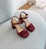 Sandalias de cuero color uva, con taco ancho, plataforma delantera y tira en el tobillo con hebilla ajustable.