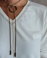 Remera blanca de manga larga con cuello en V y costuras decorativas en contraste. Incluye un lazo ajustable en el cuello con herraje metálico circular.