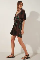Vestido corto con escote en V y mangas cortas amplias, con elástico fruncido en la cintura. Presenta un teñido tie-dye en tonos marrón oscuro y verde azulado, con un borde de bordado de hilos de lurex plateado en el escote.