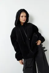 Campera tipo canguro teddy negra con capucha y cierre. El forro es de felpa color verde militar.