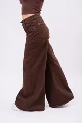 Jean wide-leg color marrón chocolate, con tiro medio, bolsillos frontales y traseros, y costuras decorativas verticales a lo largo de las piernas.