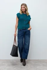 Chaleco tejido de punto con cierre frontal de botones y cuello redondo. Presenta un diseño sin mangas con textura acanalada.