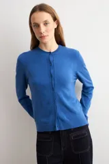 Cardigan de punto color tostado, con escote redondo, manga larga y cierre frontal de botones a tono.