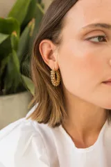 Aros de acero quirúrgico con baño en oro, con forma de aro y textura de pequeñas esferas.