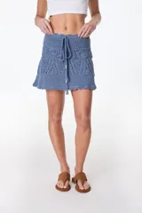 Minifalda celeste tejida al crochet con lurex plateado, cintura con cordón ajustable y diseño calado.
