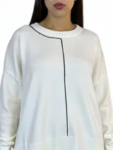 Buzo de tejido de punto color blanco, con cuello redondo y detalle de línea vertical en contraste color negro. Presenta corte relajado, mangas largas con puños acanalados y ruedo amplio con terminación acanalada.