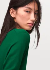 Jersey de punto fino color verde, con cuello redondo y diseño recto de manga larga.