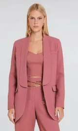 Blazer de sastrería color rosado con diseño estructurado, cuello solapa redondeado y cierre frontal con broche metálico. Cuenta con bolsillos laterales con solapa y un bolsillo superior decorativo.