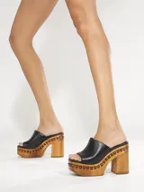 Zueco de plataforma Schutz color negro con taco alto de madera y detalles de tachas alrededor de la suela.