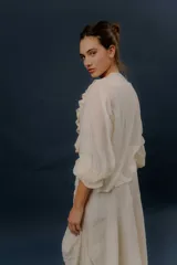 Camisa blanca de algodón con escote en V, volados delanteros y detalles de encaje en el frente y las mangas.