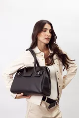 Cartera de mano estructurada de cuero vacuno rojo, con doble asa superior y detalles de charol en la parte superior. Cuenta con cierres metálicos y apliques decorativos laterales con hebillas.