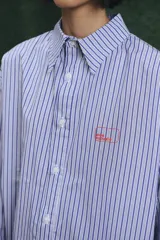 Camisa de corte oversize con estampado a rayas verticales en tonos azul y blanco, cuello clásico y cierre frontal con botones.