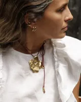 Collar con dije grande de bronce con forma orgánica y textura rugosa, suspendido de un cordón negro. Incluye cordones intercambiables.