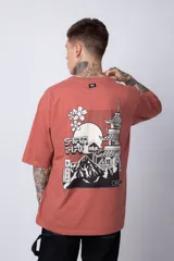 Remera de corte oversize color terracota, con cuello redondo y manga corta. Presenta un estampado circular pequeño en el pecho con motivos orientales.