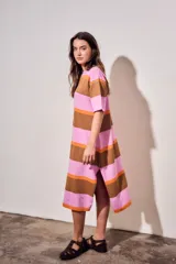 Vestido midi de tejido de punto con diseño de rayas horizontales en tonos rosa, naranja y marrón. Presenta cuello redondo, mangas cortas y un corte holgado con aberturas laterales en el ruedo.