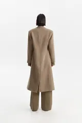 Tapado largo de silueta recta en color tostado, con hombros estructurados y solapas clásicas. Presenta bolsillos laterales con solapa y cierre frontal de dos botones.