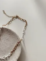 Collar de cadena con eslabones combinados en metal dorado y acrílico blanco.
