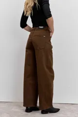 Pantalón de jean color marrón, de corte recto y tiro medio, con cierre de botón y cremallera, y bolsillos laterales.