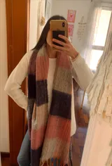 Bufanda de gran tamaño con diseño de cuadros en tonos naranja, rosa, gris, negro y beige, con flecos en los extremos.