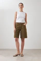 Bermuda de jean color verde oliva, corte a la rodilla, con bolsillos delanteros y traseros, y presillas para cinturón.