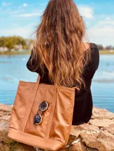 Bolso tote de cuero color marrón con doble asa de hombro y bolsillo externo con cierre.