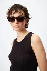 Musculosa blanca de tejido acanalado con detalle de trenzado lateral ajustable.