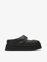 Zueco tipo Mary Jane de la marca UGG, color negro, con diseño de plataforma alta y forro interior de piel de oveja. Presenta costuras decorativas y una tira sobre el empeine.