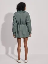 Campera larga color verde con cuello acanalado, cierre de doble sentido, bolsillos de parche grandes, cintura interior ajustable y puños con borde con volados.