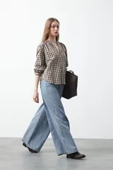 Camisa de algodón con estampado de cuadros vichy en tonos azul y blanco. Presenta escote en V con cierre frontal de botones, mangas largas con puños y un corte levemente holgado con frunces en hombros y espalda.