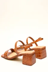 Sandalia de cuero vacuno color negro con textura de cocodrilo, taco cuadrado de 4 cm, punta cuadrada y dos tiras finas, una en el empeine y otra con hebilla en el tobillo.