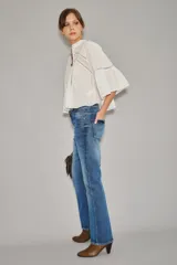 Jean de corte recto y tiro alto, confeccionado en denim azul con un lavado localizado que presenta efecto de bigotes y torceduras. Cuenta con cierre y botón frontal.