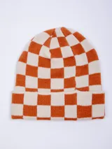 Gorro de tejido de punto con diseño a cuadros en color naranja y beige, con un parche negro con la inscripción "PIECE OF CAKE" en blanco.