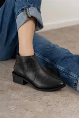 Bota corta negra de cuero con puntera fina y cierre lateral.