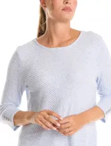 Buzo de tejido soft color beige con textura jaspeada, cuello redondo, mangas tres cuartos con detalle de botones en los puños y tajos laterales en el ruedo.