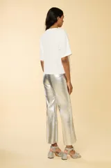 Remera blanca de corte holgado con mangas cortas acampanadas, cuello redondo y apliques de strass con forma de conchas en el frente.