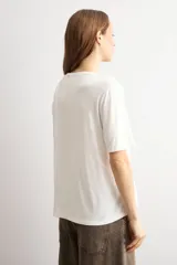 Remera negra de manga corta con panel frontal de tela broderie con diseño geométrico de rombos y espalda lisa.