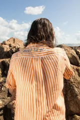 Camisa de manga corta oversize en lino rayado, con cuello camisero, cierre frontal con botones y bordado playero en el frente.