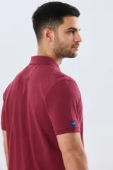 Remera polo lisa de piqué en color bordó, con cuello camisero, cierre frontal con botones y mangas cortas.