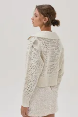 Cárdigan tejido de punto calado color crudo, con cuello polo, cierre metálico frontal y mangas largas.