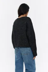 Jersey negro de punto con hilos de colores entretejidos, corte recto, escote barco y mangas largas abullonadas.