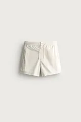 Short de baño en tejido técnico color beige claro, con cintura elástica ajustable con cordón y botón, bolsillos laterales y detalle de costuras en contraste.