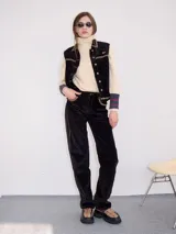 Pantalón de tiro medio confeccionado en pana negra, de corte holgado y diseño recto, con detalle de línea lateral en tono contrastante.