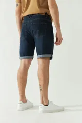 Bermuda de jean azul oscuro con bolsillos delanteros y traseros, presillas para cinturón y dobladillo en el ruedo.