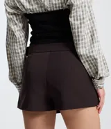 Short pollera de estilo sastre con diseño de plegado delantero, cintura estructurada y cinturón lateral integrado con hebilla metálica.