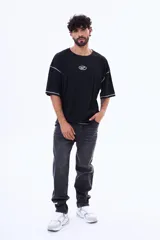 Remera negra de corte boxy con costuras a la vista en color blanco. Presenta un pequeño logo bordado en el centro del pecho y mangas cortas amplias.