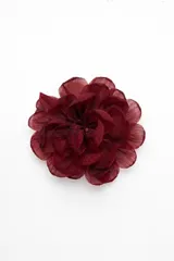 Broche en forma de flor con pétalos de tela superpuestos en color bordó.