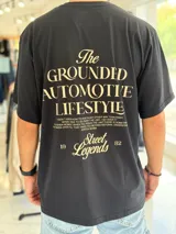 Remera oversize blanca de manga corta, con gran estampado tipográfico en color rojo en la espalda con la leyenda "The Grounded Automotive Lifestyle".
