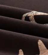 Buzo canguro marrón oscuro con capucha, cierre frontal completo y bolsillos, confeccionado en mezcla de algodón y poliéster con interior de felpa. Presenta una estampa en la espalda y mangas con diseño de huesos en tono beige claro con efecto desgastado.